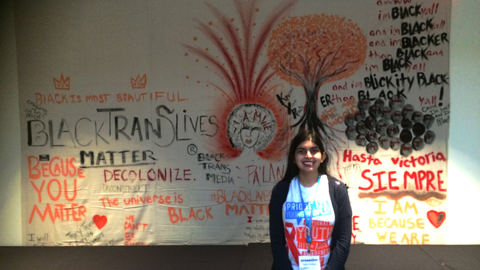 Sadia next to a mural at a conference